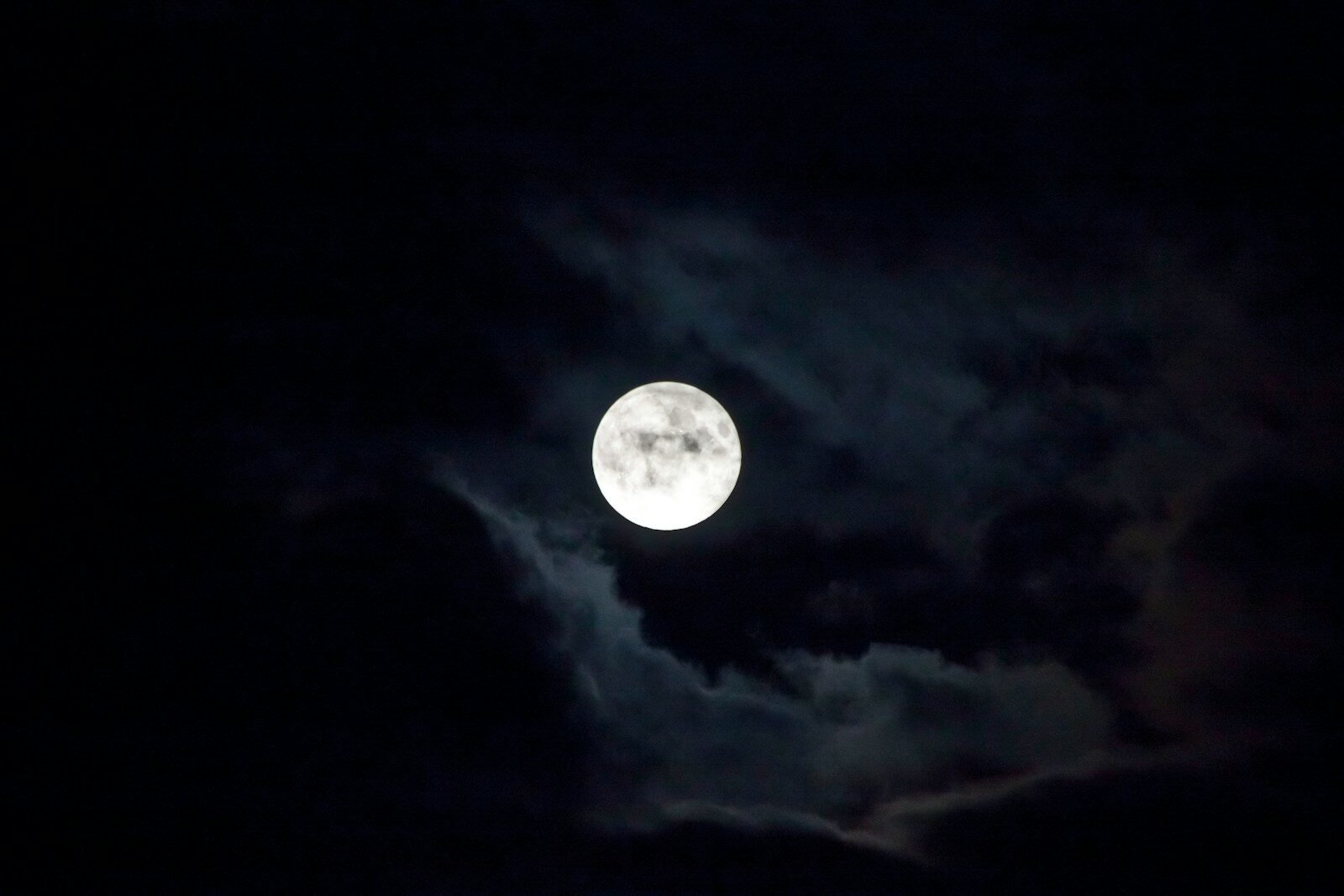 a full moon is seen through the clouds